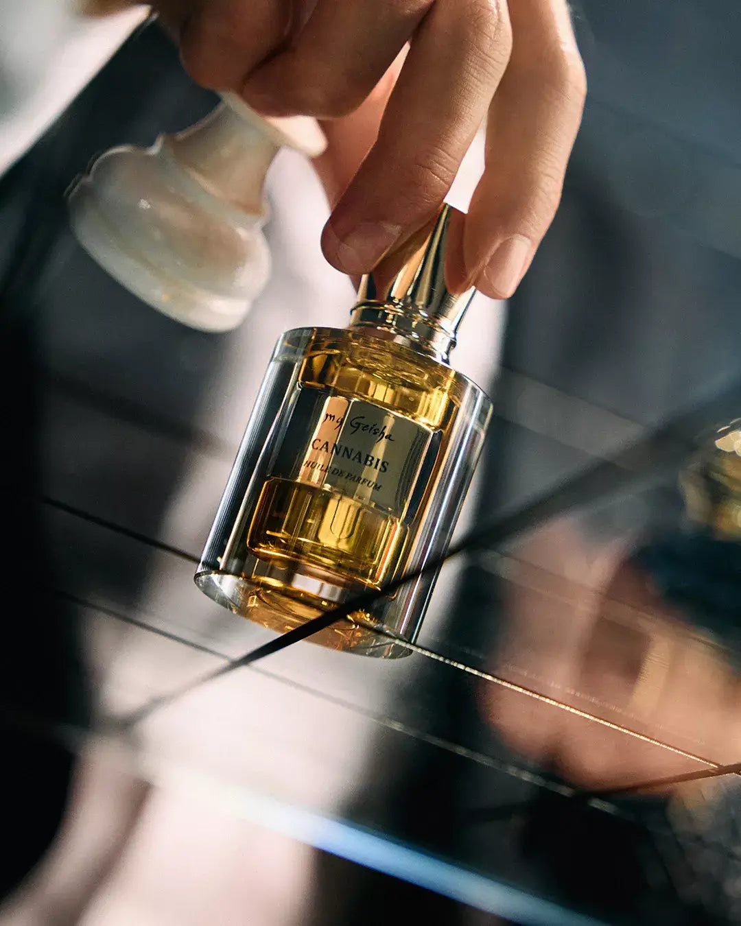 my Geisha Cannabis Huile de Parfum Premium Edition bottle with a hand holding it, blurred background