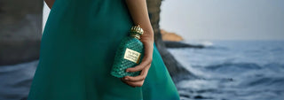 Person holding a green bottle of my Geisha Cannabis Lost Island Extait de Parfum with a blurred ocean background