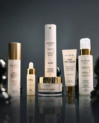 Collection of skincare products with visible my Geisha branding on a reflective surface and dark background
