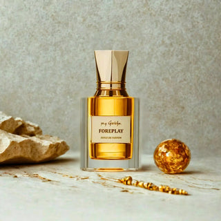Gold perfume bottle labeled 'my Geisha FOREPLAY' on a neutral background with decorative amber elements.