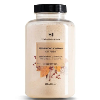 A clear plastic jar with a black lid containing beige bath powder labeled 'Sandalwood & Tobacco'.