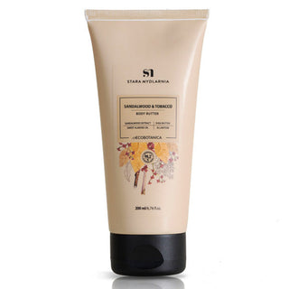 A tube of Stara Mydlarnia Sandalwood Body Butter with a label showing sandalwood and tobacco leaves, indicating the scent of the product.