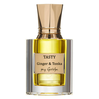 A bottle of 'TASTY Ginger & Tonka' perfume with a clear golden liquid visible inside, housed in a sleek glass container with a gold-colored cap.